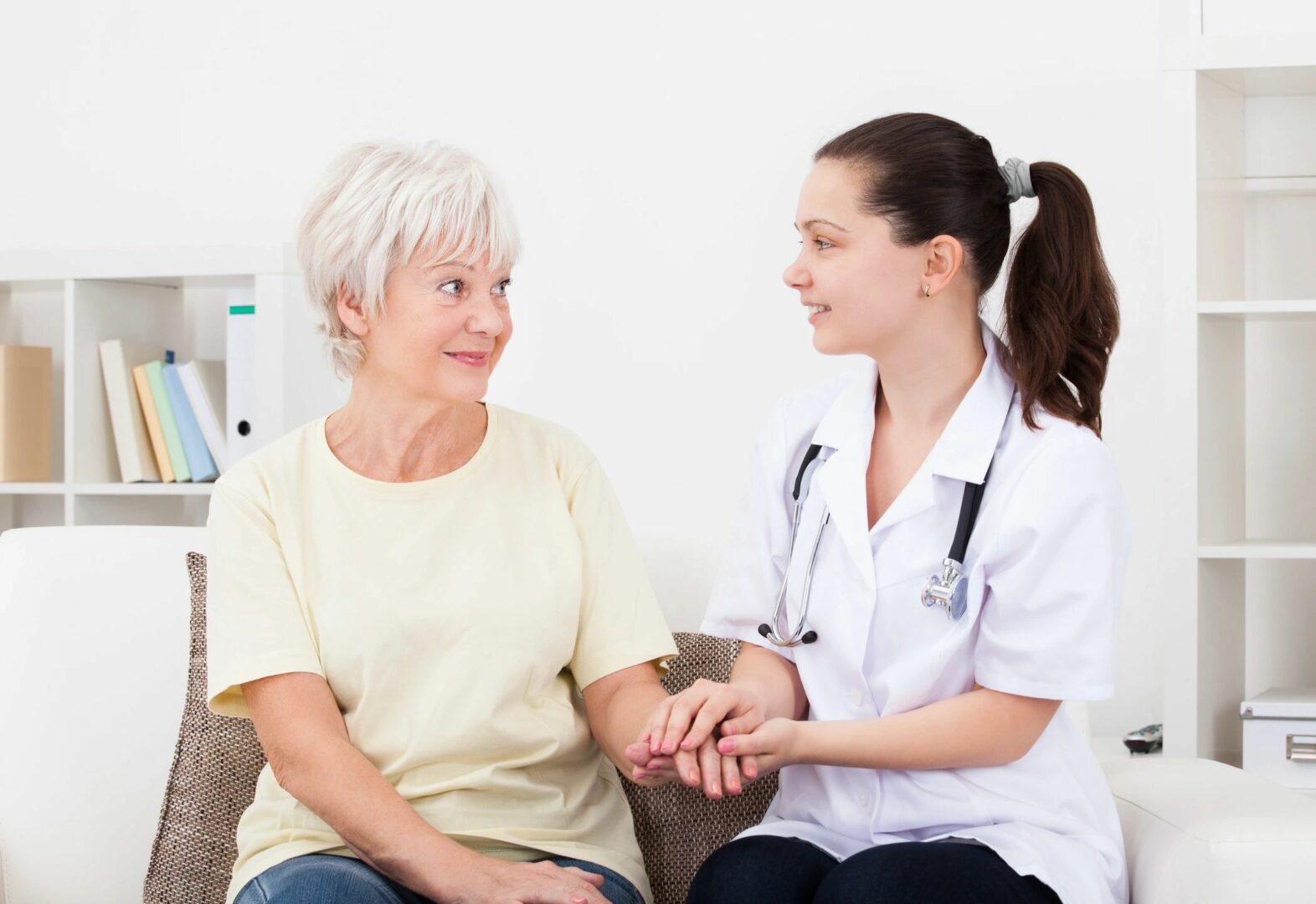 A woman sitting next to another person holding hands.