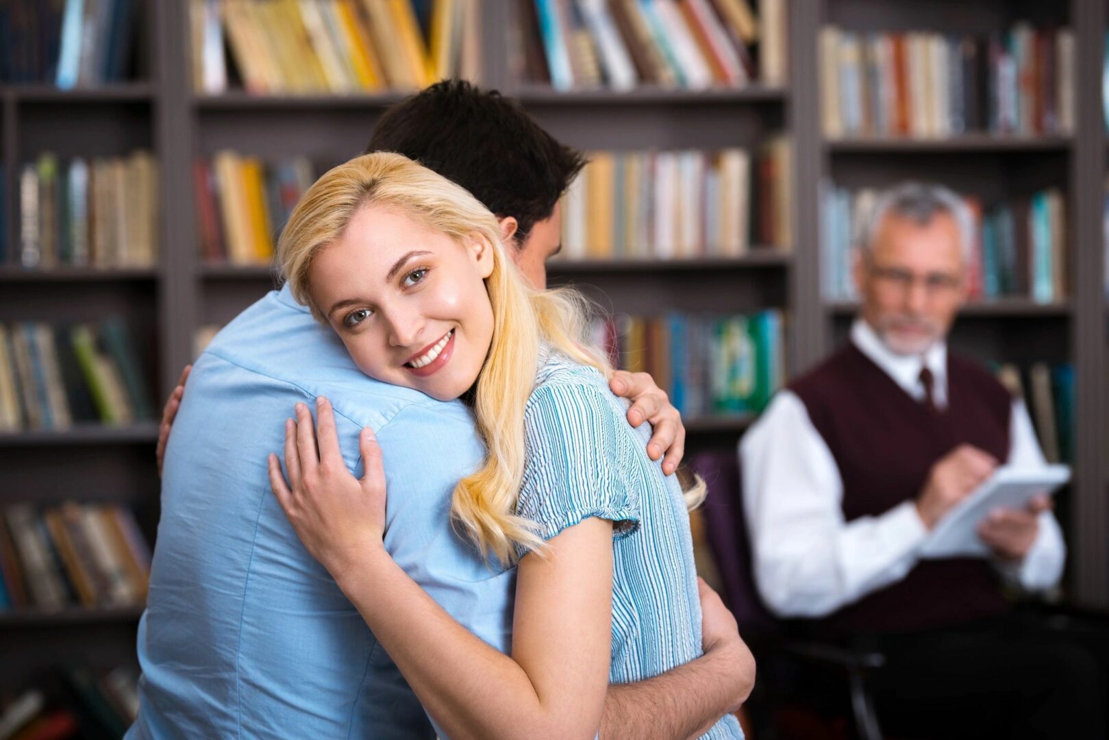 A woman hugging a man in front of another man.